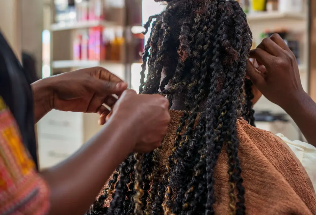 A stylist creating an intricate African braided hairstyle